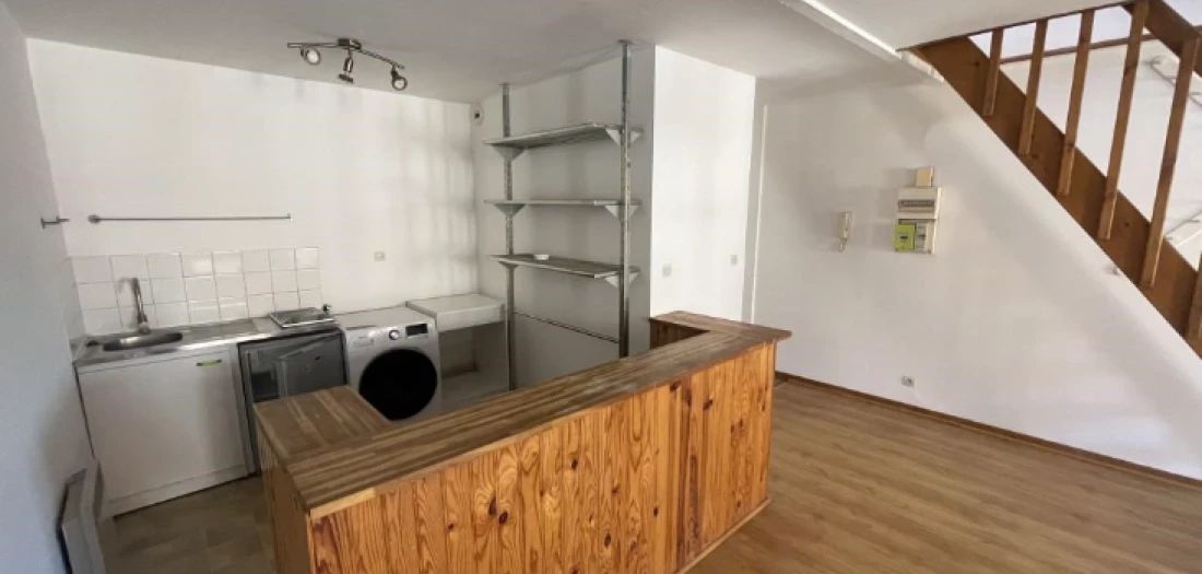 Intérieur de l'appartement avec vue sur la partie cuisine, et escalier à droite